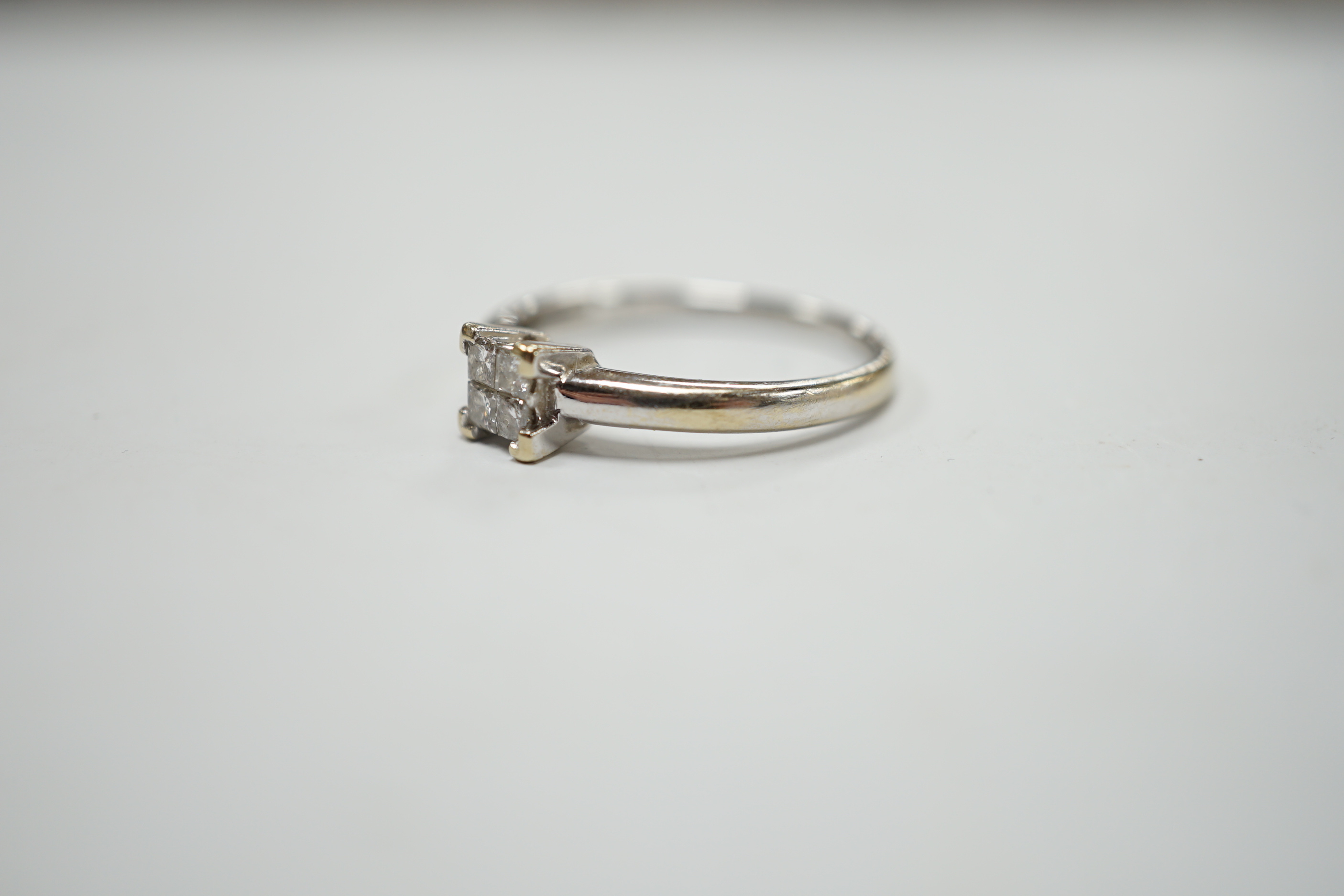 A modern 18ct white gold and four stone diamond set square cluster ring, size P/Q, gross weight 3.2 grams.